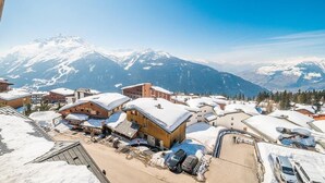 A snow-covered mountain village with wooden buildings and a clear view of snow-capped mountains in the background. - Wifi, 50m from resort center, 4th floor, view mountain, fitness, swimming pool, sauna, hammam (La Rosière Montvalezan)