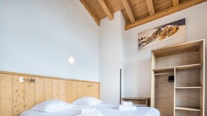 A neatly made bed with white linens and towels, a wooden headboard, a wooden wardrobe, and a painting on the wall. - Wifi, 50m from resort center, 4th floor, view mountain, fitness, swimming pool, sauna, hammam (La Rosière Montvalezan)