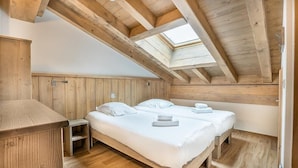 Een houten kamer met twee bedden, een dakraam en een houten bank.