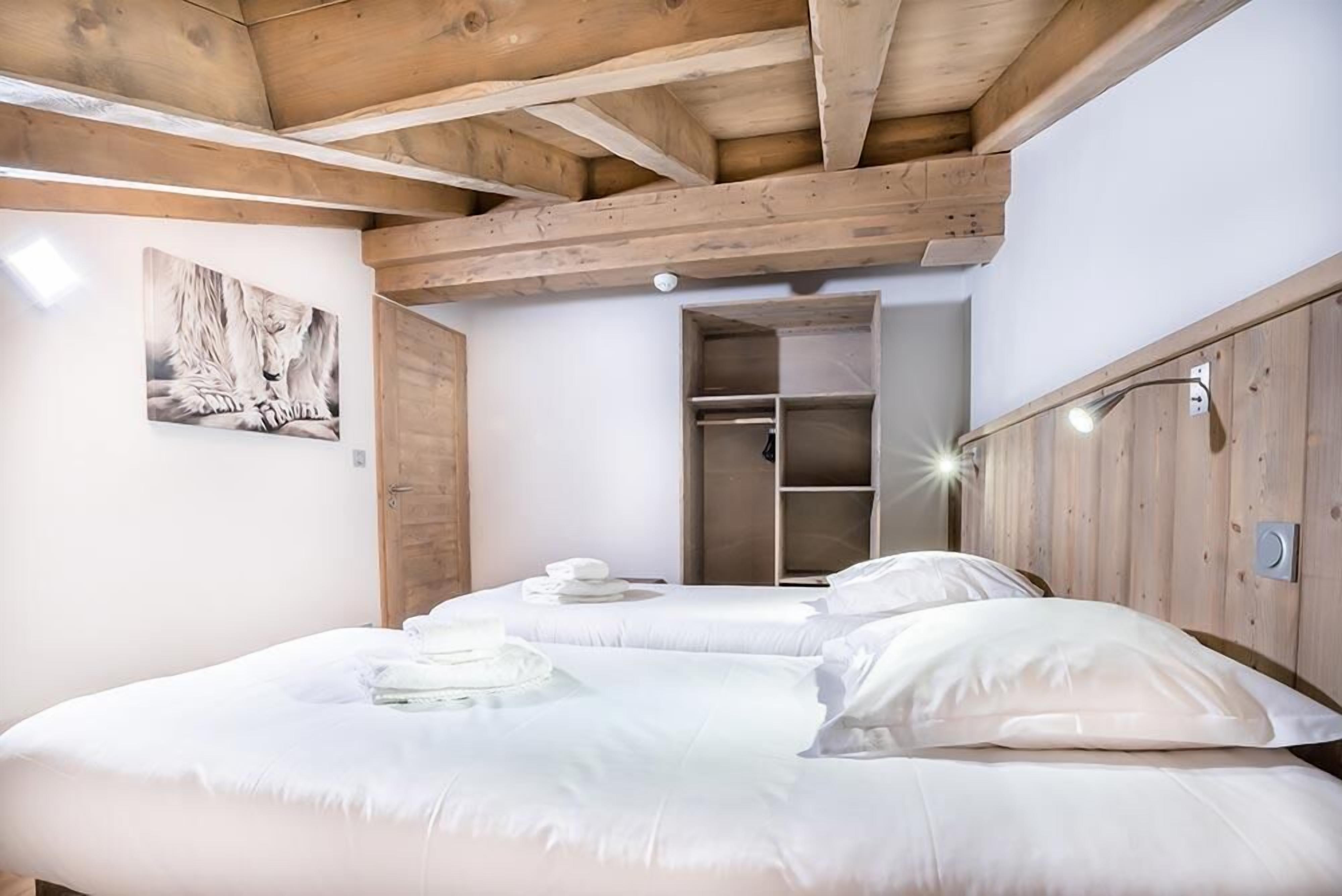 Un dormitorio con techo de madera, una cama con ropa de cama blanca, un armario de madera y un cuadro enmarcado en la pared.