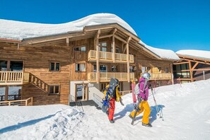 A wooden chalet with a balcony and a ski lift in the background.