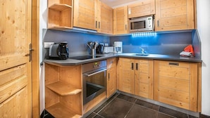 A modern kitchen with wooden cabinets, a microwave, a coffee maker, and a sink.