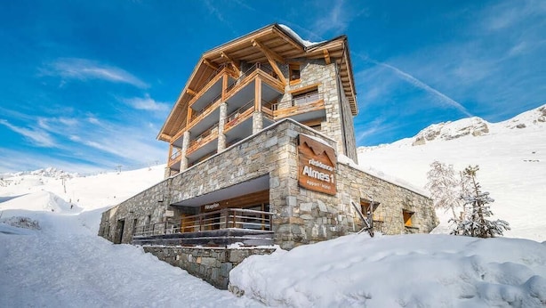 A multi-story stone building with a ski lift in the background, surrounded by snow.