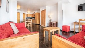 A modern interior with a wooden sofa, a small table, and a red ottoman.