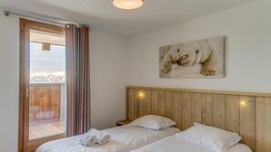 A bedroom with two beds, a wooden headboard, a window with curtains, and a polar bear painting on the wall. - Wifi, ski-in/ski-out & foot of the slopes, 3rd floor, view valley, fitness, swimming pool, sauna (La Rosière Montvalezan)