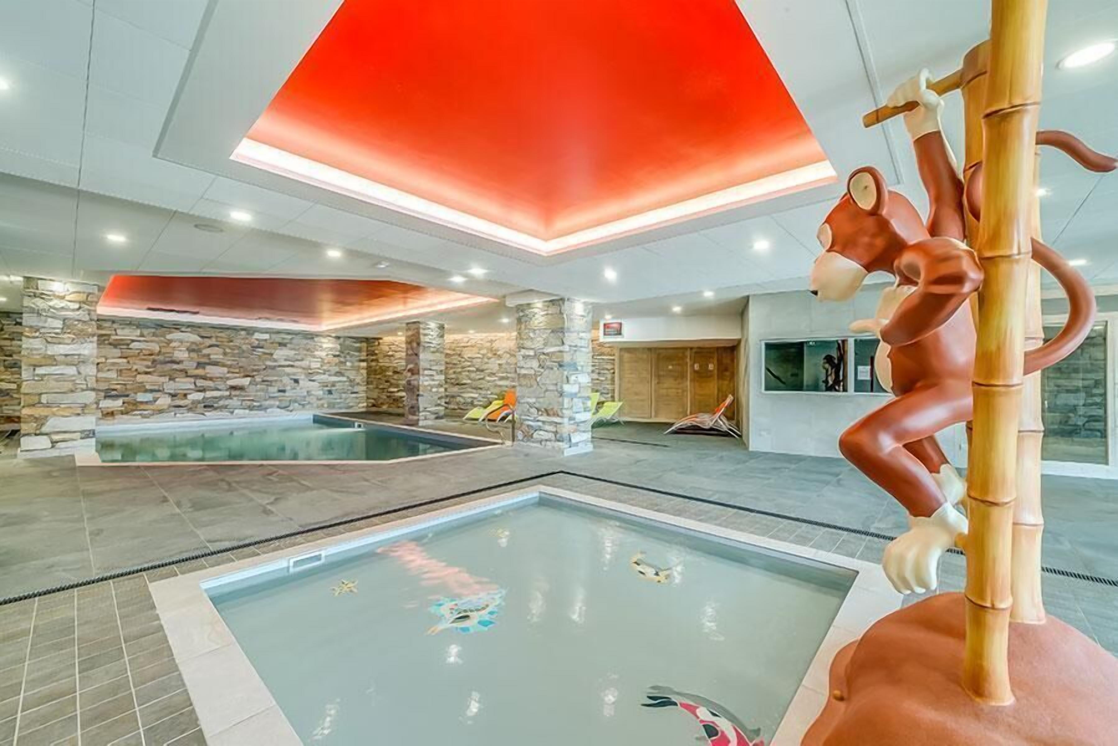 An indoor swimming pool area with a stone wall and a large red ceiling.