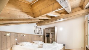 A bedroom with two beds, wooden ceiling beams, a wardrobe, and a mirror. - Wifi, ski-in/ski-out & foot of the slopes, 4th floor, view mountain, fitness, swimming pool, sauna (La Rosière Montvalezan)