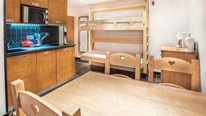 Una cocina compacta con armarios de madera, un microondas y una litera con cabecera en forma de corazón.