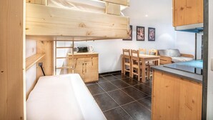 Una cocina compacta con un banco integrado, armarios de madera y un comedor con sillas.