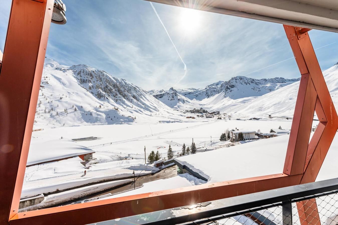 A snow-covered mountain landscape viewed through a window with a metal frame.