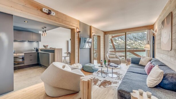 Ein modernes Interieur mit Küche, Sitzgelegenheit und großen Fenstern.