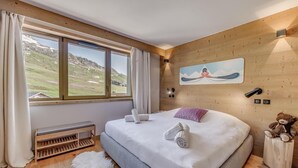 Ein Schlafzimmer mit einem großen Bett, einer Bank, einem flauschigen Teppich, einem Teddybären und einem Bild an der Wand.
