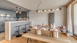 Eine moderne Küche mit einer zentralen Kochinsel, Barhocker und einem für das Frühstück gedecktem Esstisch.