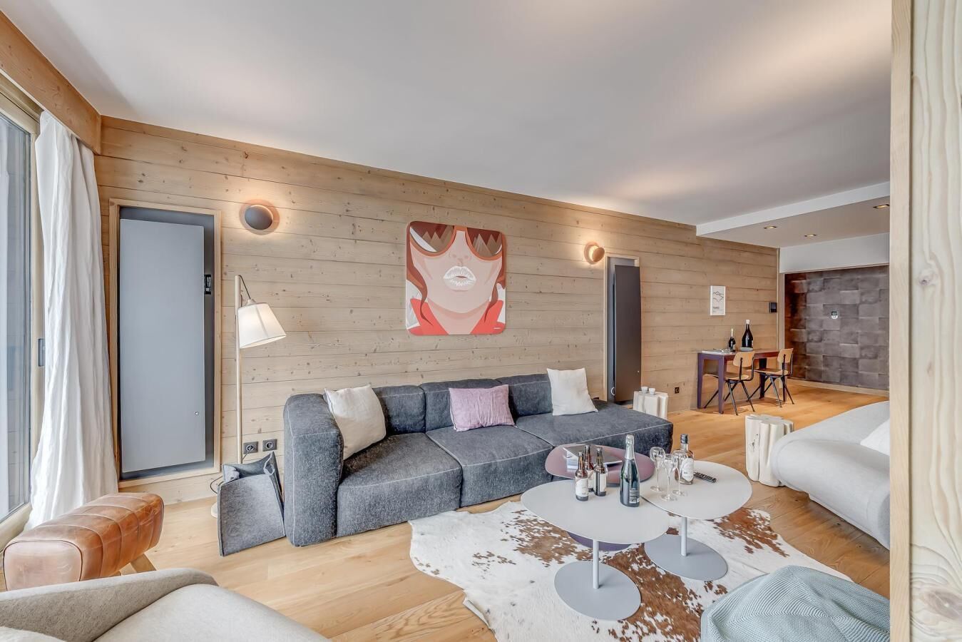 En moderne stue med en grå sofa, en hvid måtte og en trævæg.