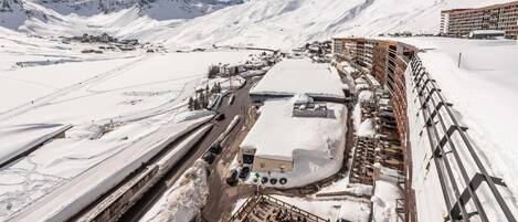 A snow-covered mountainous area with a ski resort, including a building with multiple floors and a parking area.