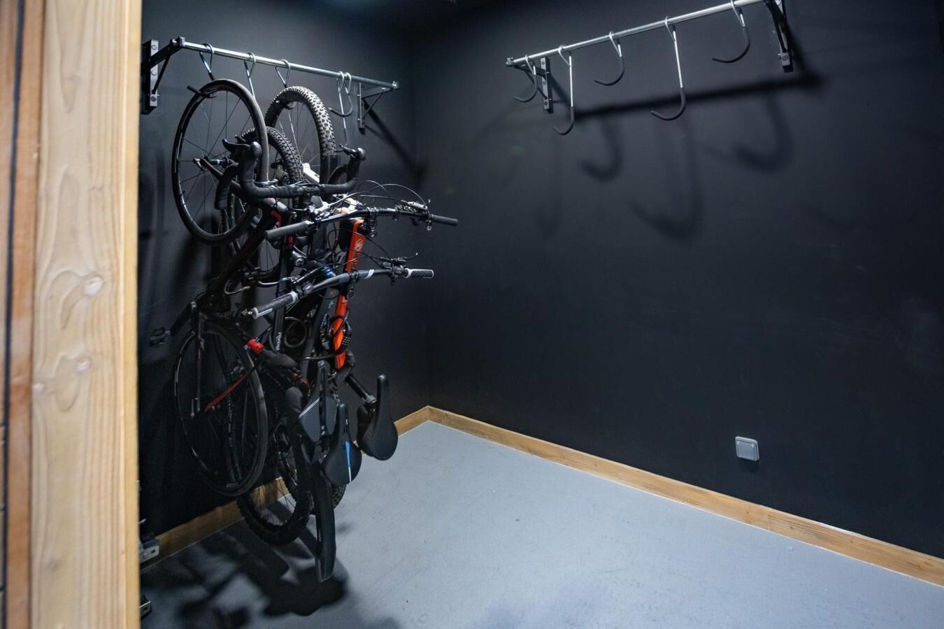 A room with a bike rack holding two bicycles and a wall-mounted hook.