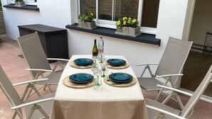 A table set for four with a beige tablecloth, four blue plates, and a bottle of wine. - " LE 16 BAIE DE SOMME, STUDIO D HOTE"
TERRASSE ET JARDIN  (Friville ESCARBOTIN)