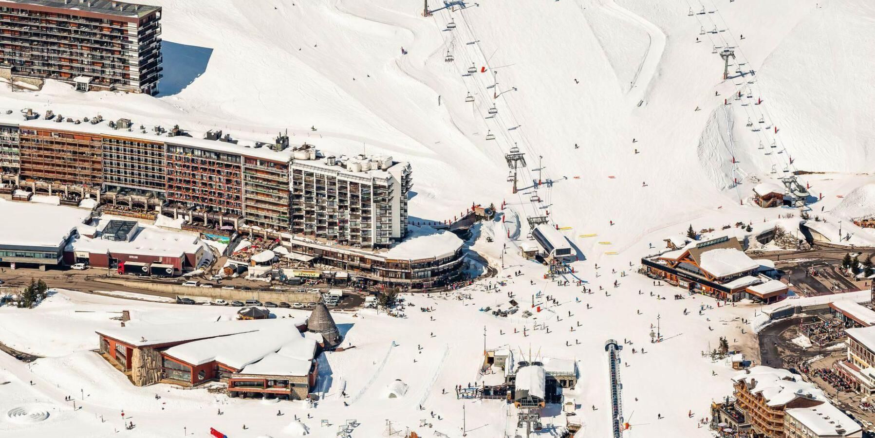 A ski resort with multiple buildings, including a large hotel with multiple floors and a ski lift.