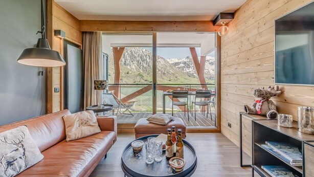 A modern living room with a leather sofa, a coffee table with bottles, and a view of a deck with outdoor furniture. - 200m from ski slopes, 4th floor, view lake, balcony, ski locker, 50m², Tignes (Tignes)