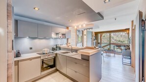 A modern kitchen with a built-in oven, a sink, and a countertop. There is a dining area with a table and chairs visible through an open door. - 200m from ski slopes, 4th floor, view lake, balcony, ski locker, 50m², Tignes (Tignes)
