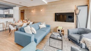 A modern living room with a blue sofa, a grey sofa, and a coffee table. There is a dining area with a table and chairs. - 200m from resort center, 3rd floor, view lake, balcony, ski locker, 75m², Tignes (Tignes)