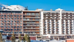 A multi-story hotel with balconies, a ski slope in the background, and snow-covered mountains. - 200m from resort center, 3rd floor, view lake, balcony, ski locker, 75m², Tignes (Tignes)