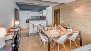 A modern kitchen with a central island, a dining area with a wooden table and white chairs, and a wooden wall with a light fixture. - 200m from resort center, 3rd floor, view lake, balcony, ski locker, 75m², Tignes (Tignes)