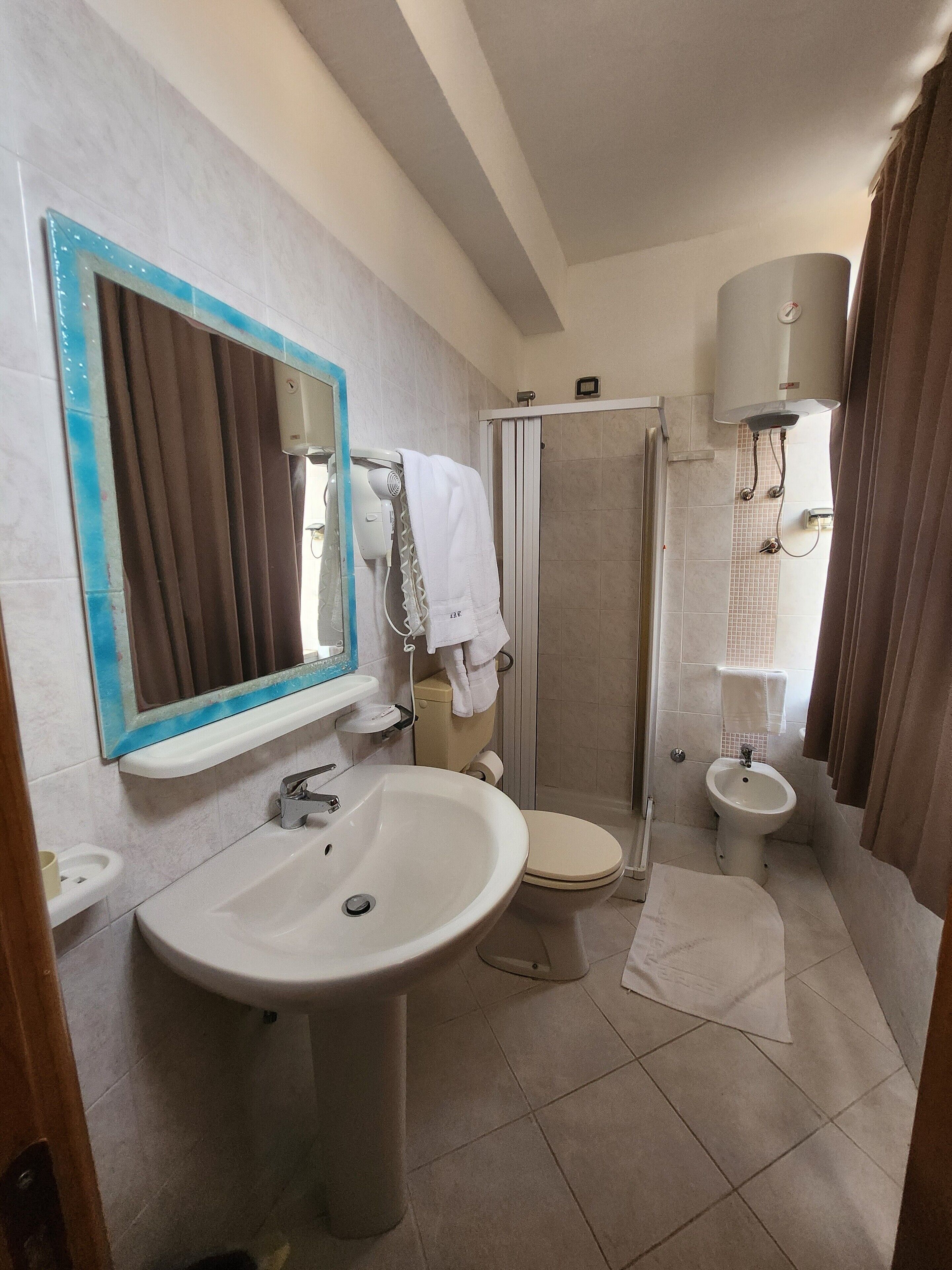 Un baño con un lavamanos grande, inodoro, bidé y zona de ducha.