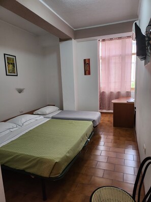 Une chambre avec deux lits, une petite table et une chaise.
