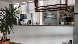 Una cocina moderna con encimera de madera, una planta en maceta y un amplio ventanal con cortinas.