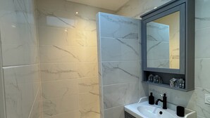 Ein modernes Badezimmer mit Oberlicht, großem Spiegel und Waschtisch.