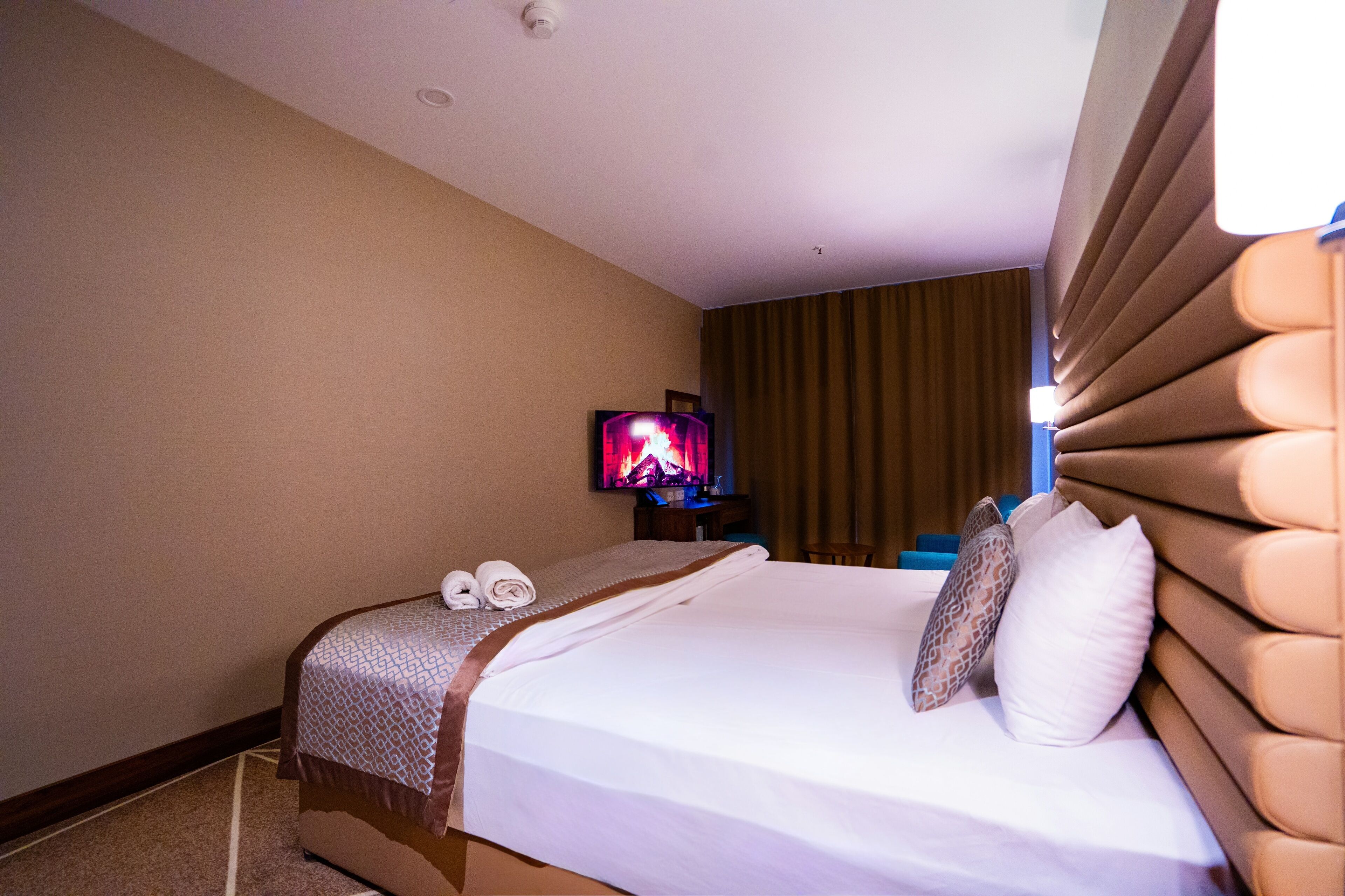 A hotel room with a bed, a television, and a window with curtains.