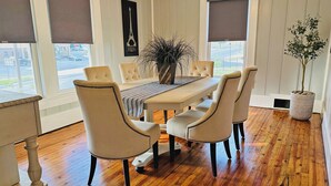Comedor con piso de madera, una mesa blanca y seis sillas tapizadas con detalles de cuentas.