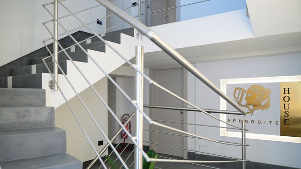 A modern staircase with metal railings and grey steps, leading to a room with a sign that reads "HOUSE APHRODITE". - Aphrodite House (Pompei)