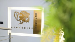 A sign with the text "HOUSE APHRODITE" and a stylized image of a woman holding a lyre. - Aphrodite House (Pompei)