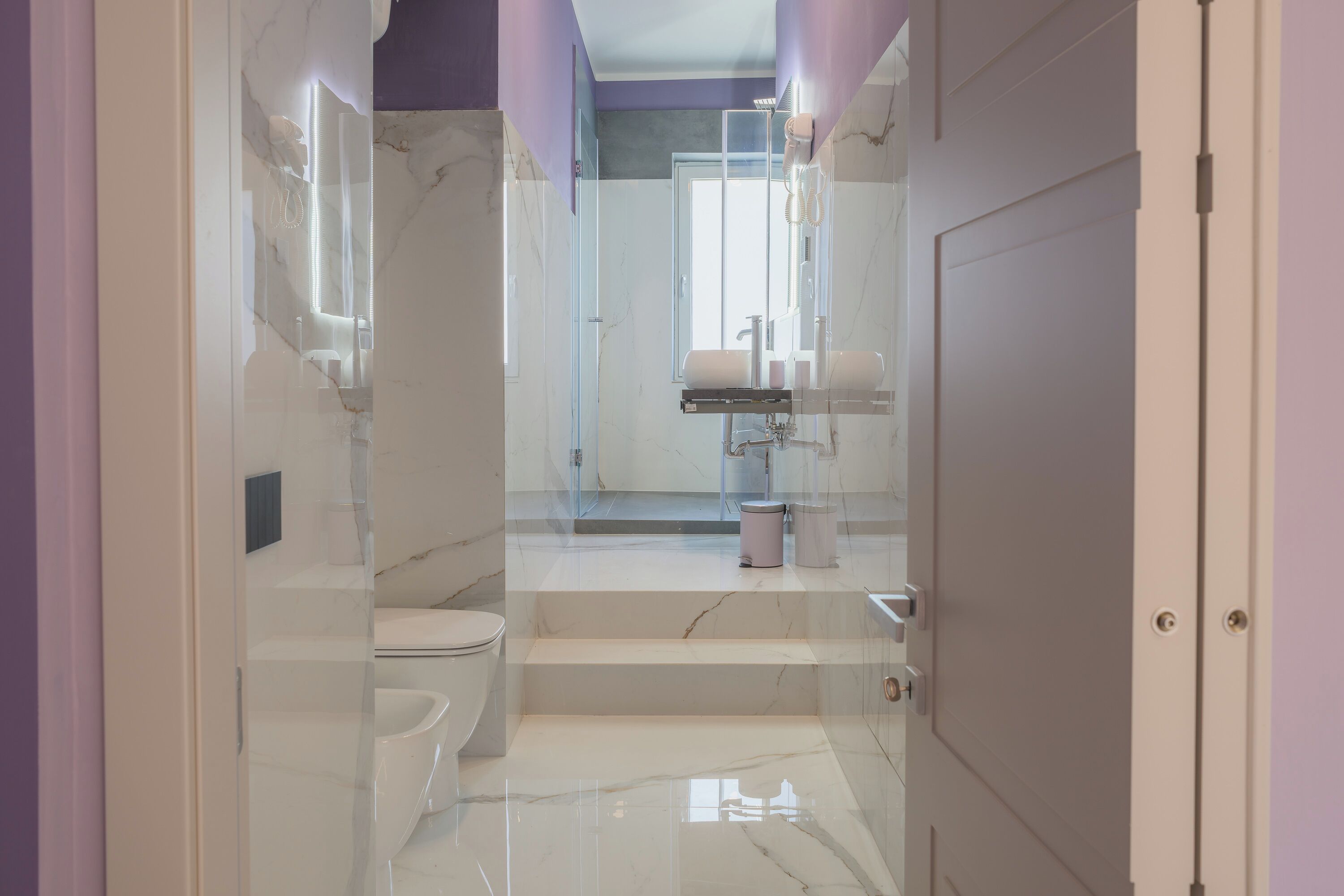 A modern bathroom with a glass shower enclosure, a toilet, and a sink.