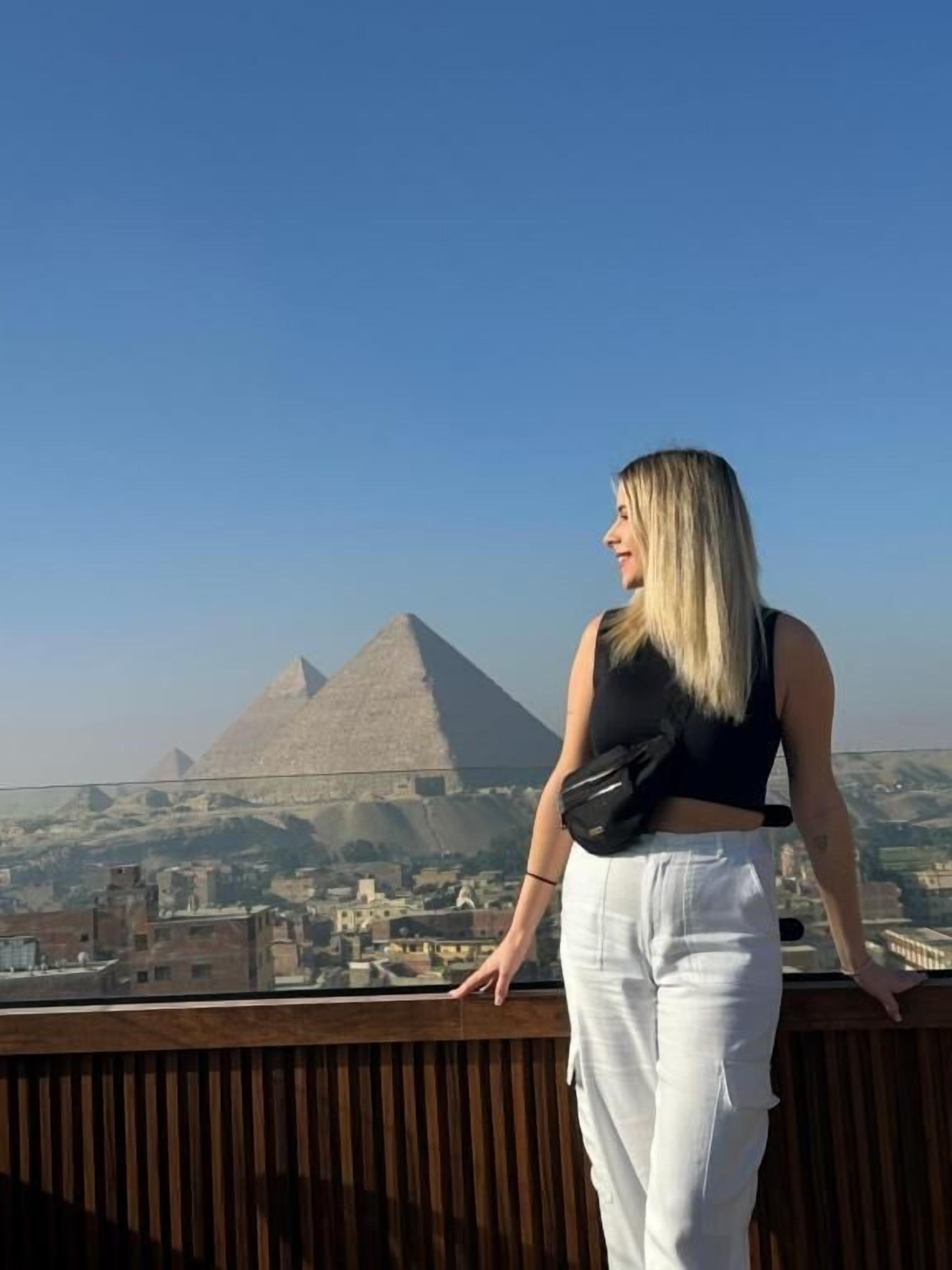 A person standing on a balcony overlooking a pyramid.
