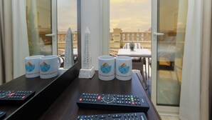 A table with two remote controls, three mugs, and a small pyramid model. - Crowne pyramids palace (Giza)