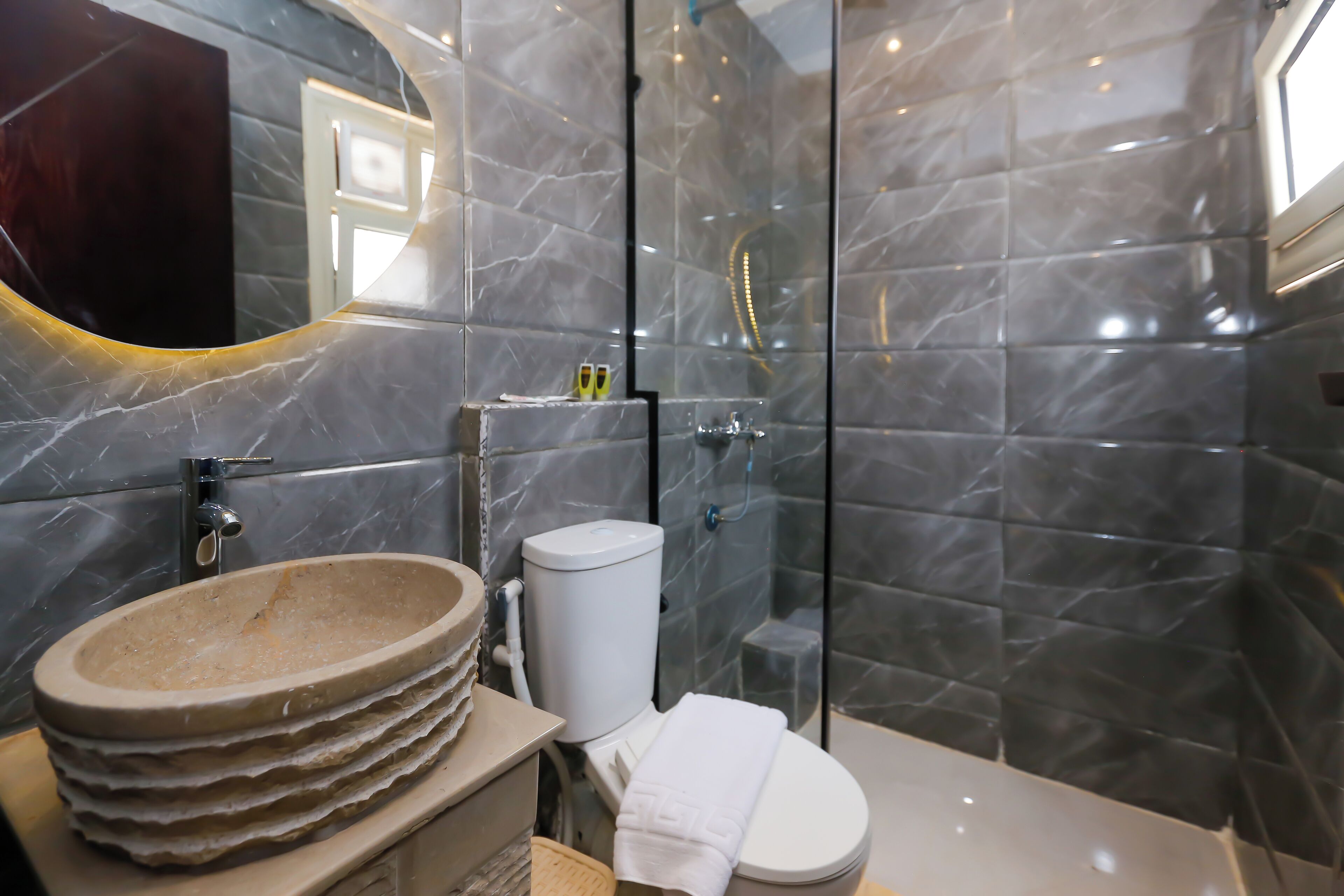 A bathroom with a marble sink, a toilet, and a glass shower enclosure.