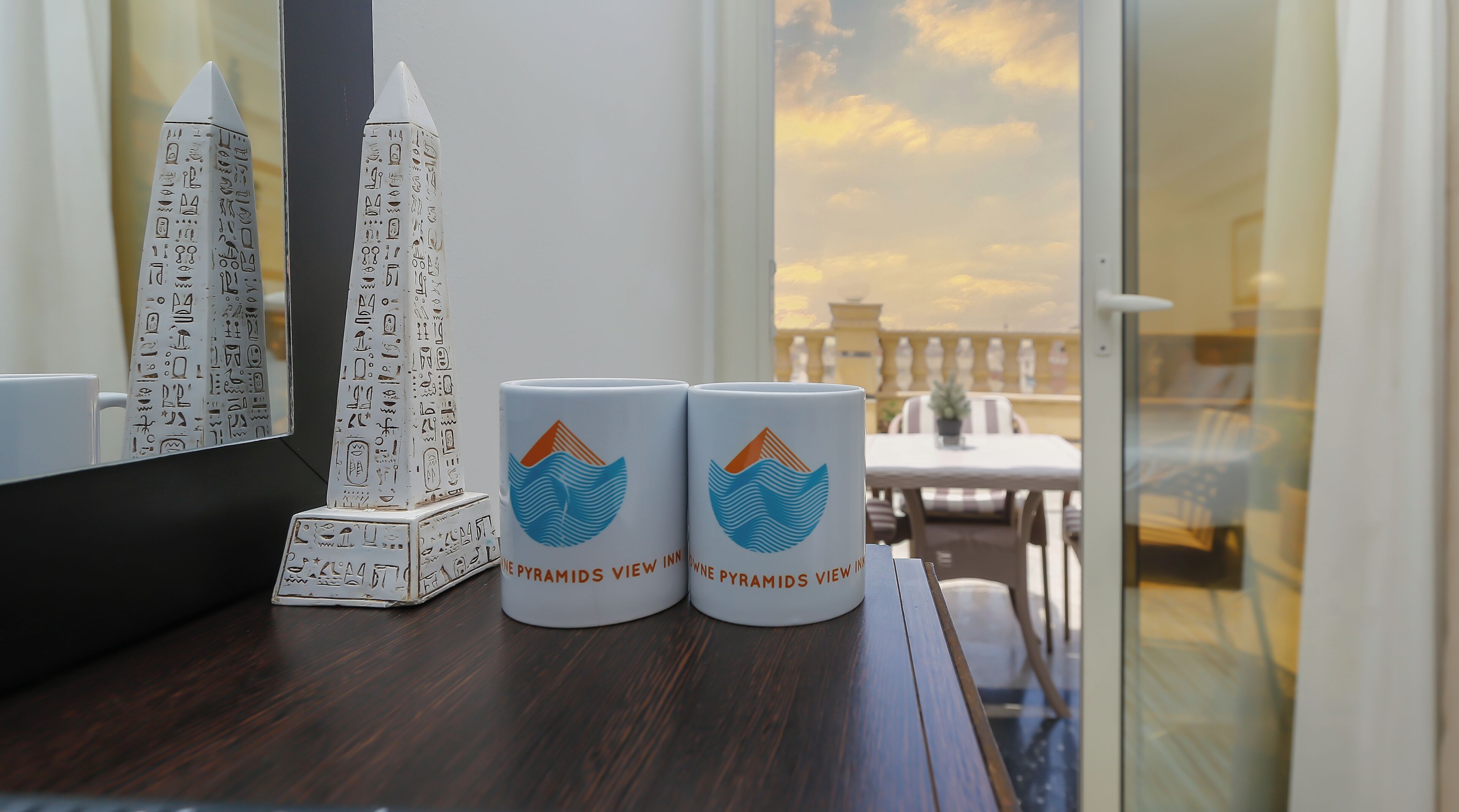 A table with two mugs and two pyramids on a wooden surface.