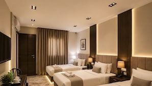 A hotel room with three beds, a desk with a coffee maker, and a TV. - Crowne pyramids palace (Giza)