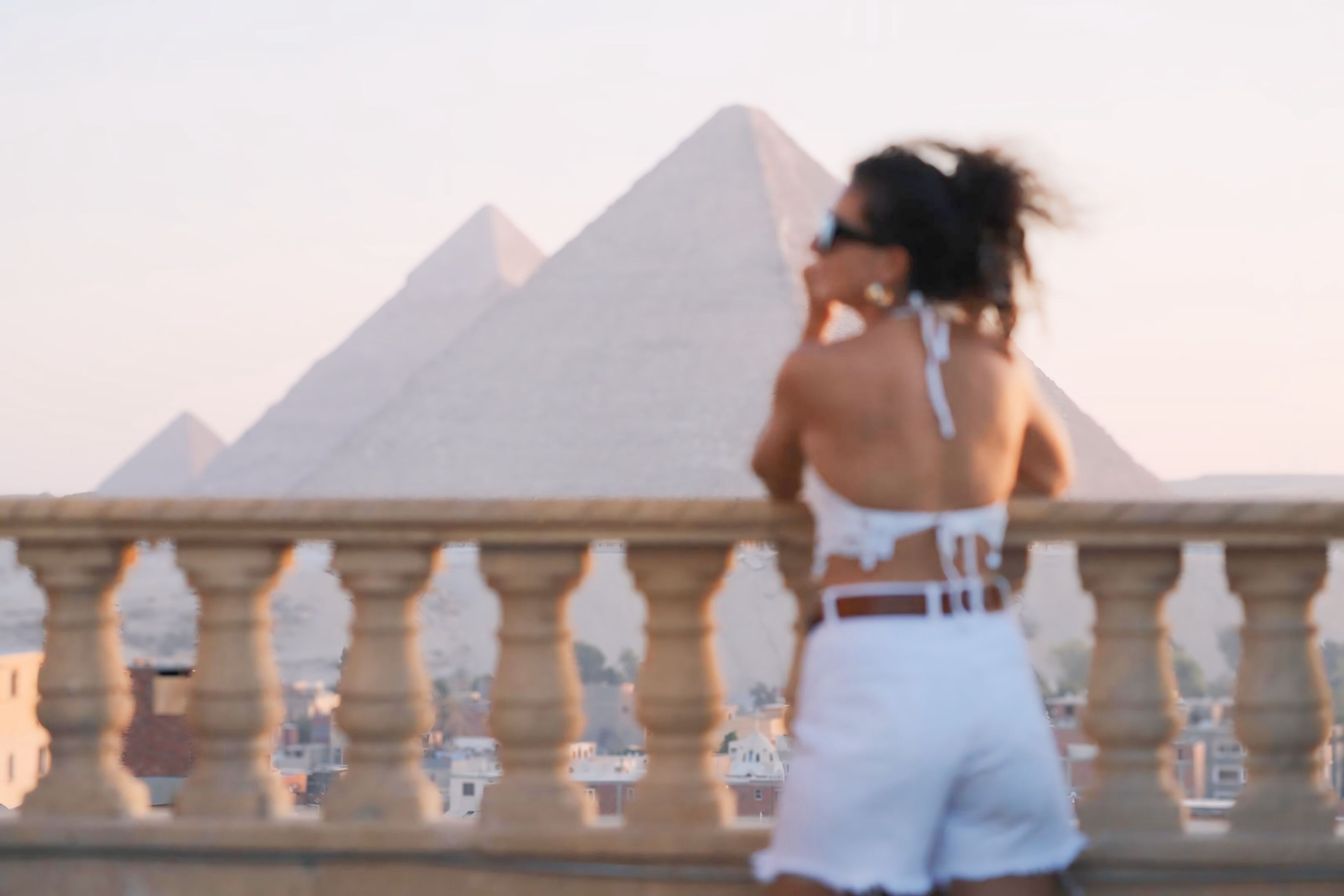 A person standing on a balcony with a view of the pyramids.