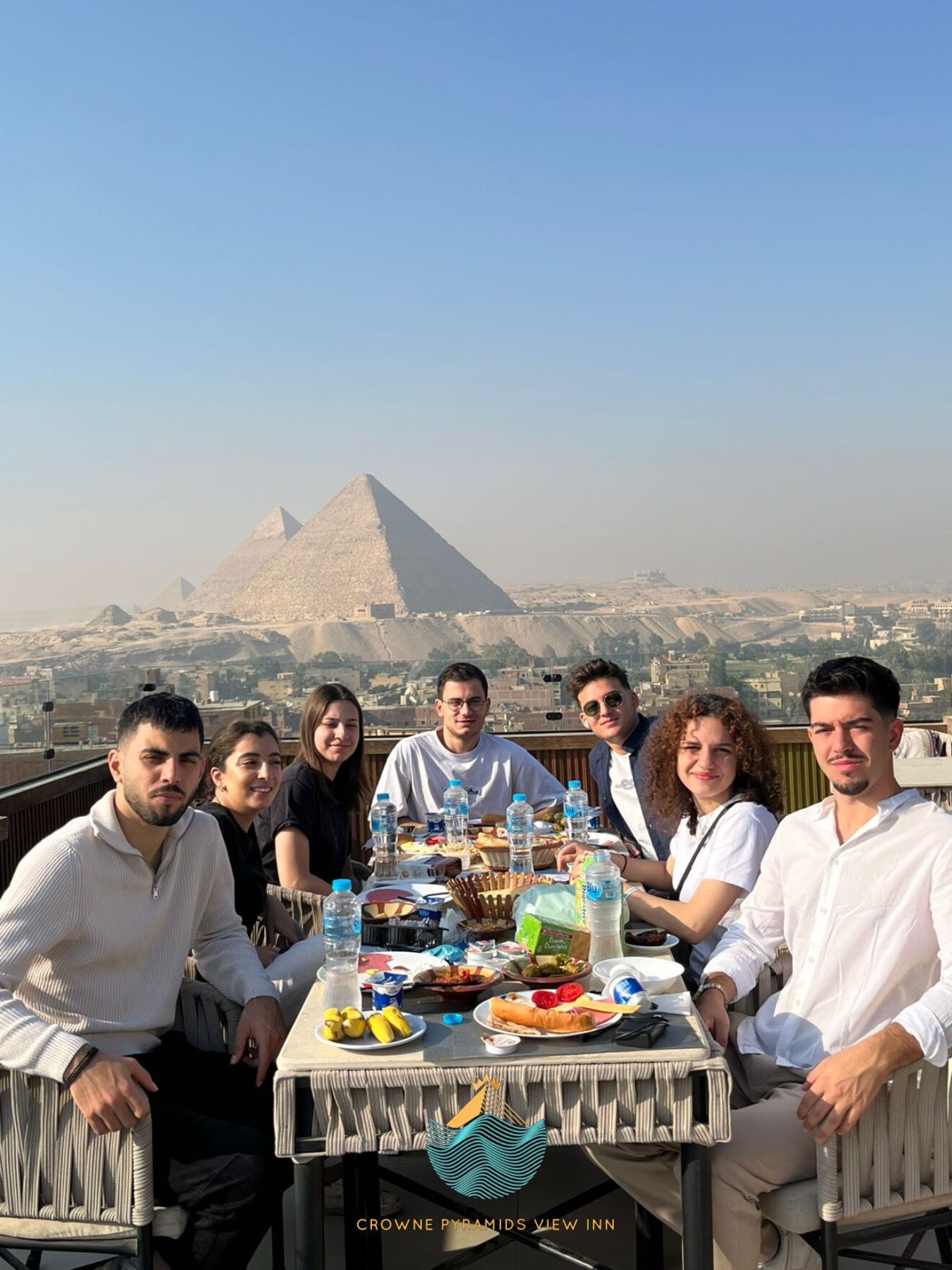 A group of people dining at Crowne Pyramids View Inn with a view of the pyramids in the background.