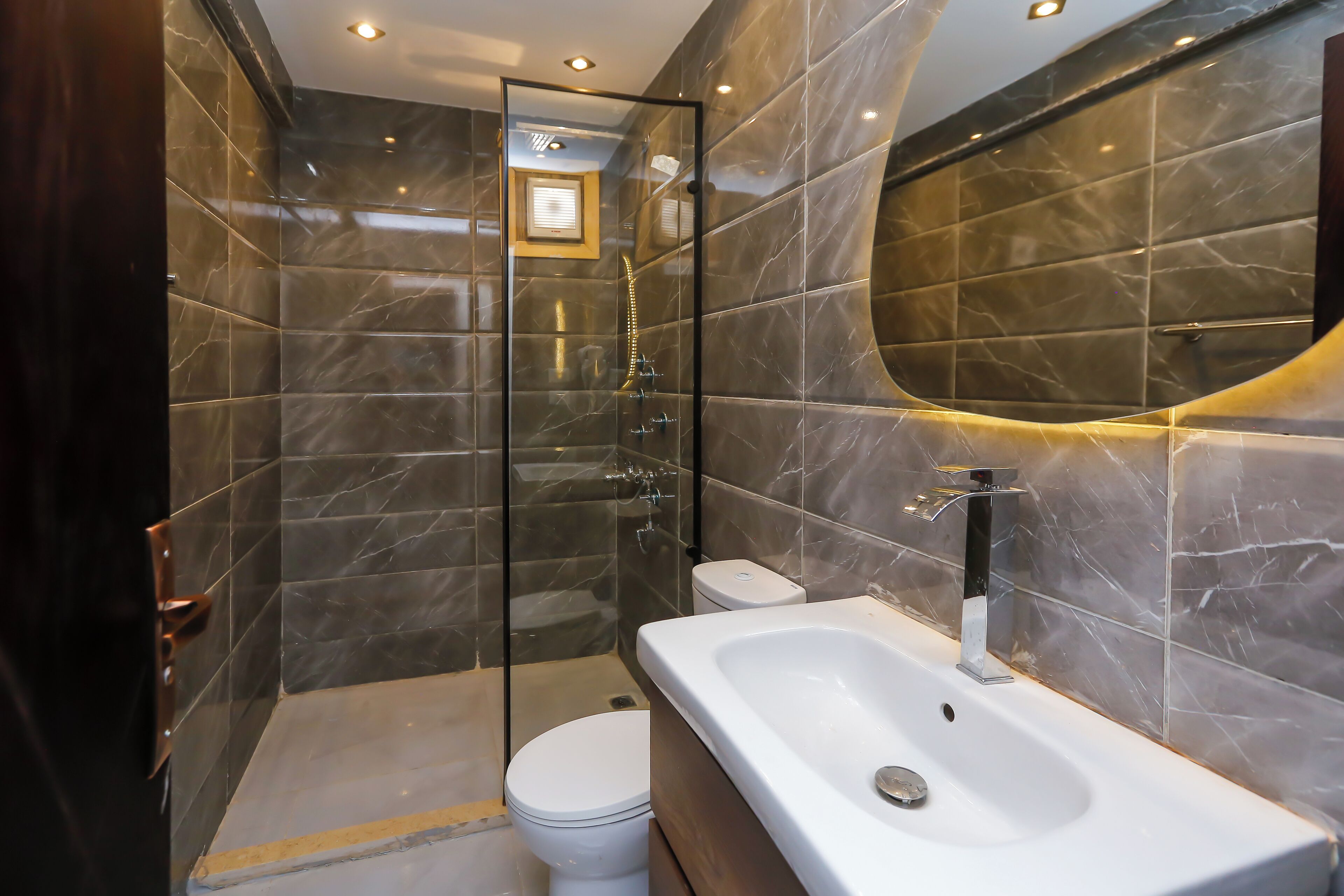 A modern bathroom with a glass-enclosed shower, a white toilet, and a large bathtub.