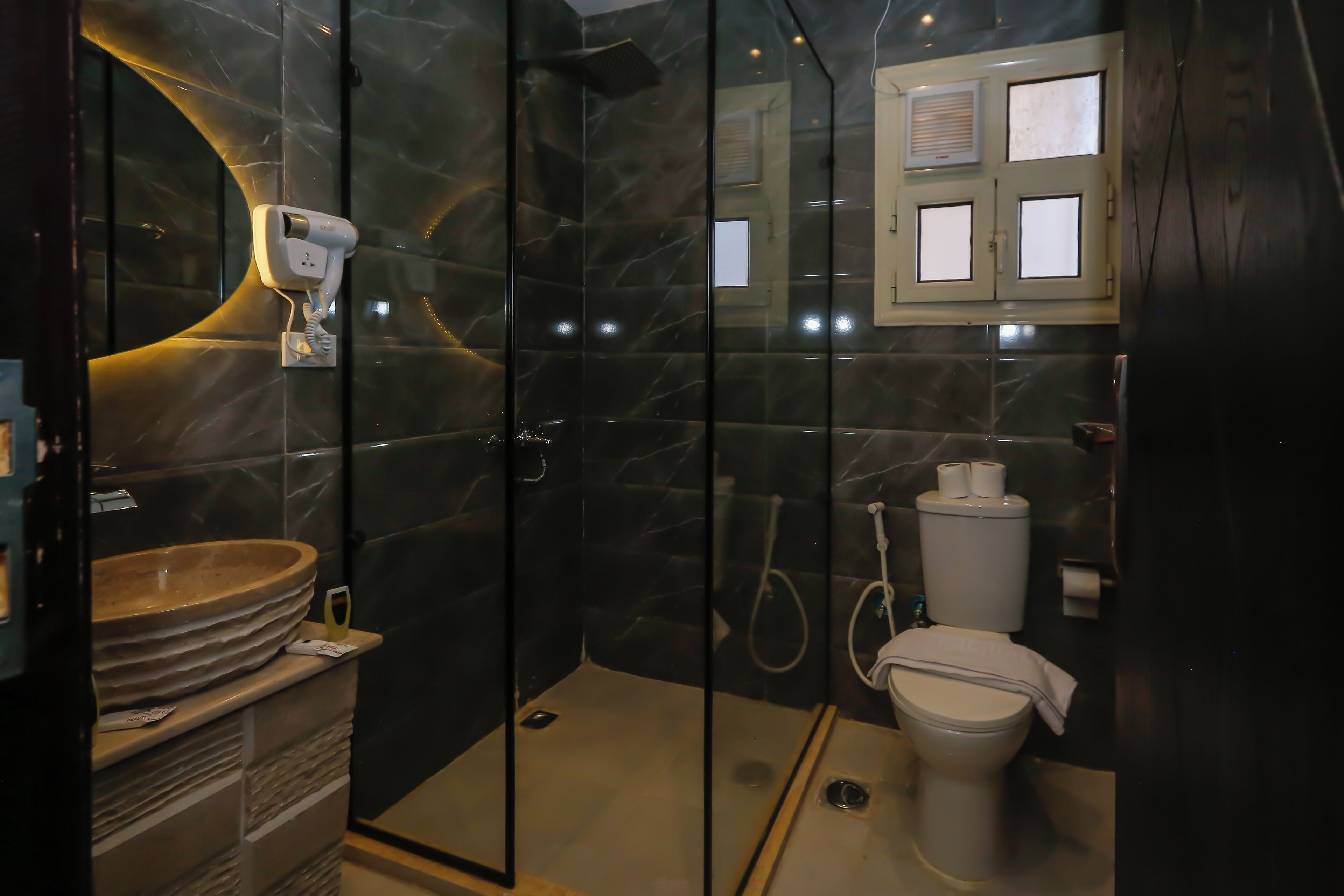 Une salle de bain moderne avec une douche à parois de verre, un lavabo en marbre et des toilettes.