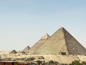 The Great Pyramids of Giza with surrounding desert landscape and ancient ruins. - Crowne pyramids palace (Giza)