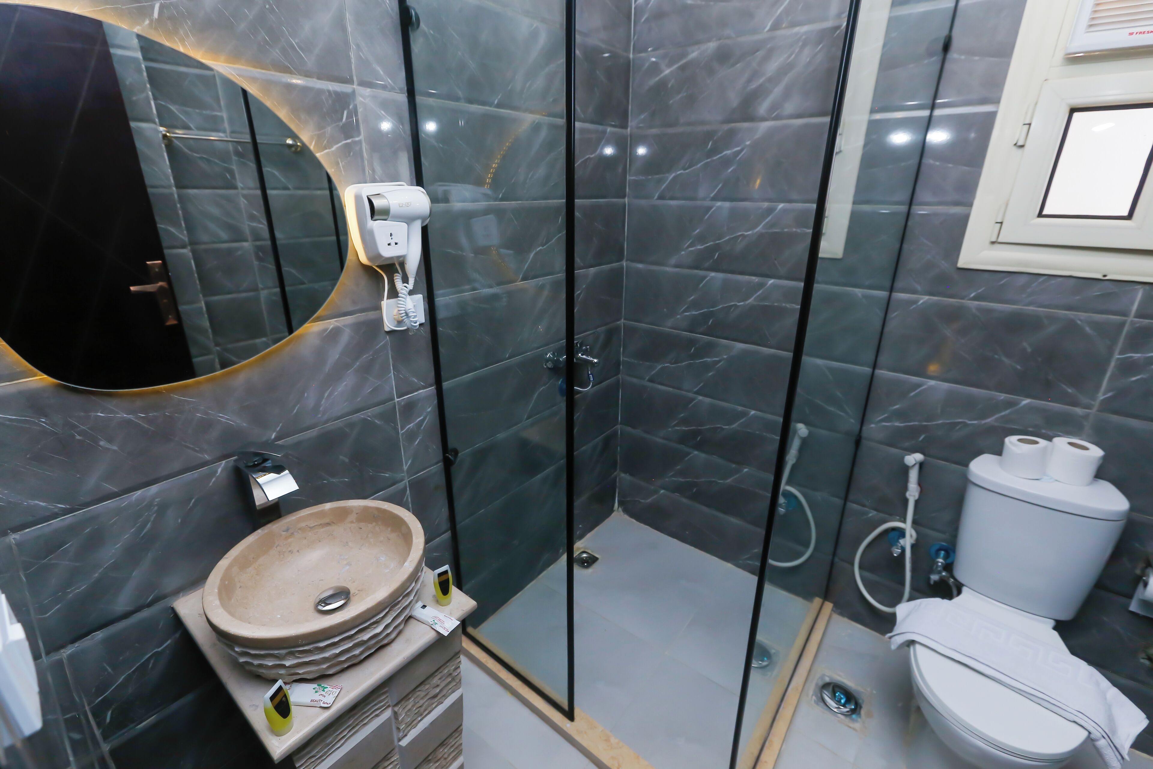 Une salle de bain moderne avec une douche à parois de verre, un lavabo avec un receveur en marbre et des toilettes.