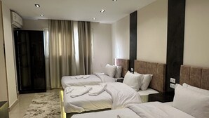 A hotel room with two beds, a large window with curtains, a modern headboard, and a marble floor. - Crowne pyramids palace (Giza)