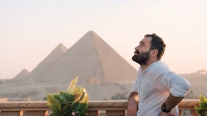 A person standing on a balcony overlooking the pyramids.