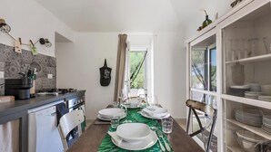 Une cuisine avec une table à manger dressée pour six personnes, un réfrigérateur blanc et un meuble contenant de la vaisselle.
